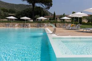 a large swimming pool with chairs and umbrellas at Agriturismo Le Ghiandaie in Piana di Caiazzo