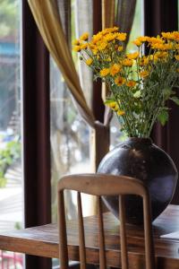 a vase with yellow flowers sitting on a wooden table at Dechiu in Hoi An