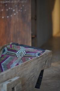 a wooden bench with a colorful cushion on it at Dechiu in Hoi An