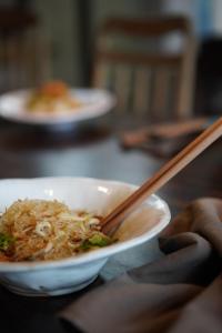 a person is holding a bowl of food with chopsticks at Dechiu in Hoi An
