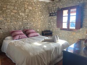 1 dormitorio con cama y pared de piedra en Masía La Perera, en Morella