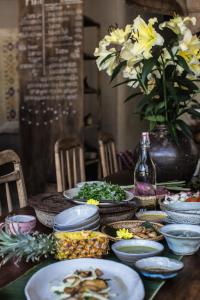 a table with plates of food and a vase with flowers at Dechiu in Hoi An