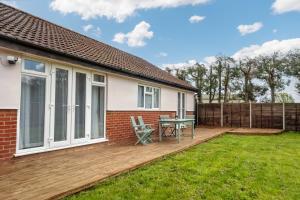 a deck with a table and chairs on a house at Mill House Bungalow in Potter Heigham