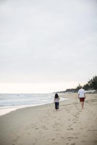 a couple of people walking on the beach at Dechiu in Hoi An