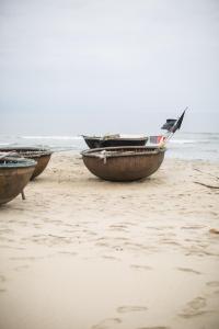 three boats sitting on a beach near the ocean at Dechiu in Hoi An