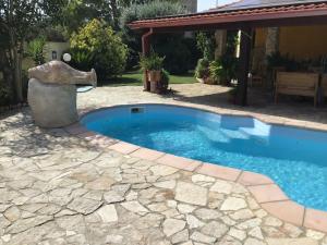 a swimming pool with a statue next to a house at Apartment in Villa, Beach 3 minutes walk, spiaggia 3 minuti a piedi in Su Forti