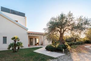 una casa blanca con un árbol en el patio en Villa Gioielli en Noto