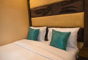 a bed with two pillows and a painting on the wall at Gardens Executive Suites in Kikuyu