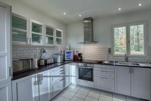een witte keuken met witte kasten en apparaten bij Crazy Villa Ecottay 61 - Heated pool & sauna - 2h from Paris - 30p in La Loupe