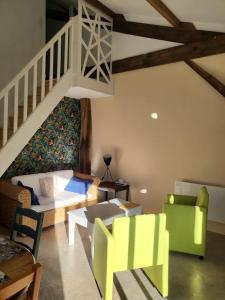 a living room with yellow and green furniture and a staircase at Cottage cosy à la campagne in Queyssac