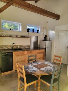 Cottage cosy à la campagne في Queyssac: مطبخ مع طاولة خشبية مع كراسي ومطبخ مع حوض وثلاجة