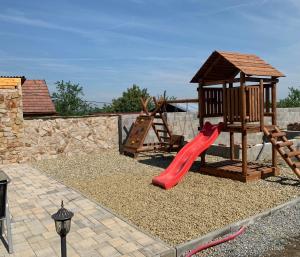 een speeltuin met een rode glijbaan en een houten speelplaats bij Café de la Crème in Kuželov