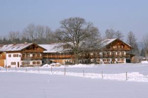 een groot houten huis in de sneeuw met een veld bij Braunhof in Bad Feilnbach