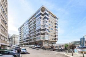 Apartamento Magnifico em Oeiras في باكو دي أركوس: مبنى كبير به سيارات تقف في موقف للسيارات