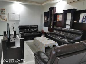 a living room with leather furniture and a table at Fig House Villa with Heated Swimming Pool & Firepit in Al ‘Aqar