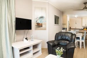 a living room with a chair and a television at LA CRETE SANDS NO 7 in Uvongo Beach