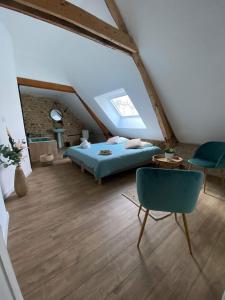 1 dormitorio en el ático con 1 cama, mesa y sillas en Sophie LE FEUVRE - Soins Energétiques, en Baugé