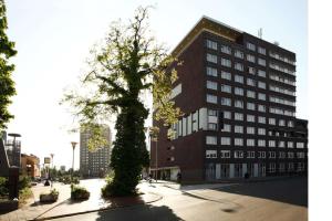 un grand bâtiment avec un arbre devant lui dans l'établissement NH Groningen Hotel, à Groningue