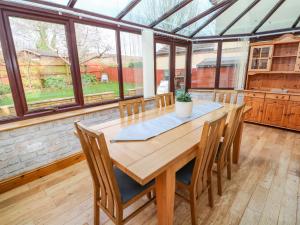 a conservatory with a wooden table and chairs at Cherry Tree House in Penzance