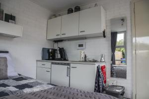 una cocina con armarios blancos y una cama en una habitación en Emmen bed and breakfast, en Emmen