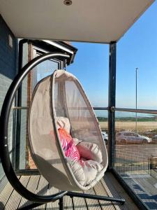 a baby sitting in a swing on a porch at The Sun Deck Apartment - Westbrook Bay Beach - By Goldex Coastal Breaks in Kent