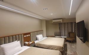 um quarto de hotel com duas camas e uma televisão de ecrã plano em Garden City Plaza Hotel no Cairo