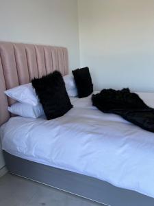 una cama con almohadas negras encima en Sibani@ Dolphin coast, en Ballito