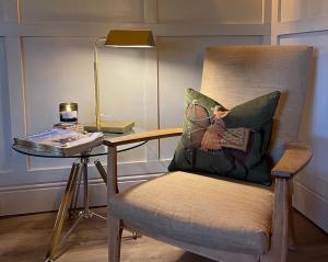 a chair with a pillow and a table with a lamp at The Stable, Yew Tree Farm Holidays, Tattenhall, Chester in Chester