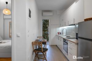 kuchnia z białymi szafkami, stołem i łóżkiem w obiekcie Aether Apartment by LobbySquare w Atenach +10 zdjęć