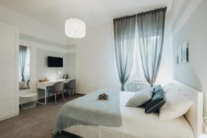 a white bedroom with a bed with a desk and a window at Realkasa Graziella in Bologna