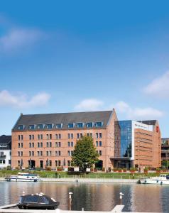 a large building with a boat in a body of water at Hotel Hafenspeicher in Leer