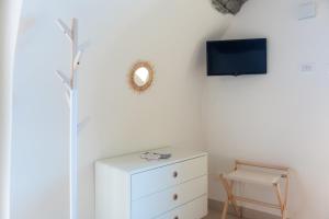 ein weißes Zimmer mit einer Kommode und einem Spiegel in der Unterkunft La casa dei tre pesci - Appartamento Alborella in Torno