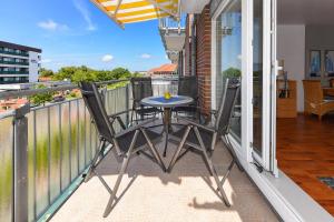 einen Balkon mit einem Tisch und 2 Stühlen darauf in der Unterkunft Nordseewelt Nordseegartenpark in Bensersiel