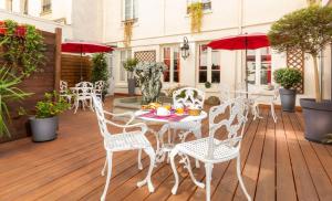 d'une terrasse avec des chaises blanches, des tables et des parasols rouges. dans l'établissement Agate Hôtel, à Paris 37 autres photos