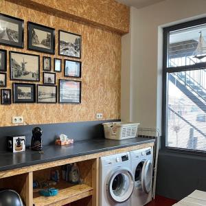 een wasruimte met een wasmachine en foto's aan de muur bij L'Ancora in Sint Annaland