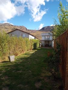 a yard with a fence and mountains in the background at Casa Patagónica Los Charitos in El Chalten