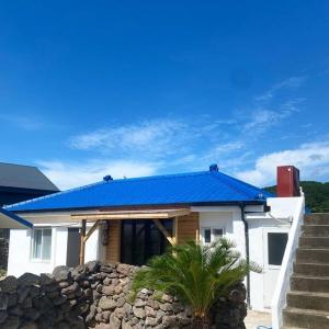 濟州的住宿－Gawkji House 곽지집，蓝色屋顶和石墙的房子