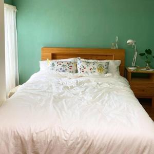 uma cama com lençóis brancos e almofadas num quarto em Gawkji House 곽지집 em Jeju