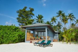 una casa en la playa con sillas y porche en Kuredu Island Resort & Spa, en Kuredu