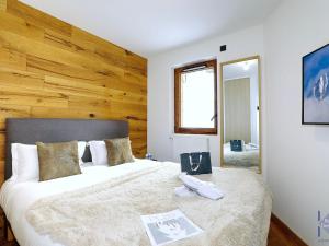 Appartement Courchevel, 4 pièces, 6 personnes - FR-1-664-14 في كورشوفيل: غرفة نوم بسرير كبير وبجدار خشبي