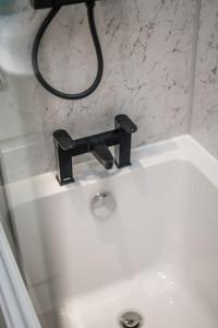 a white bathroom sink with a black faucet at Sea View Luxury Apartment 3 bedrooms Free Parking - By Coast Apartments in Arbroath