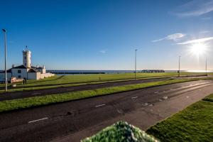an empty road with a lighthouse in the distance at Sea View Luxury Apartment 3 bedrooms Free Parking - By Coast Apartments in Arbroath