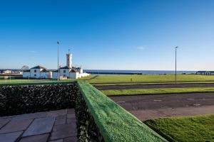a park with green grass and a lighthouse in the background at Sea View Luxury Apartment 3 bedrooms Free Parking - By Coast Apartments in Arbroath
