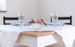 a white table with a flower in a white bowl on it at Homely in Heidenheim