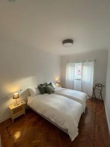 um quarto com uma grande cama branca e 2 candeeiros em ASF Home em Lisboa