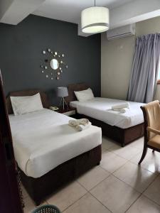 a hotel room with two beds and a chair at Hotel Atlantis in Maputo