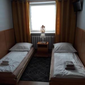twee bedden in een kleine kamer met een raam bij Willa ASPEN in Szklarska Poręba