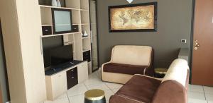 a living room with a couch and a chair and a television at Hotel Residence Aurora in Paderno Dugnano