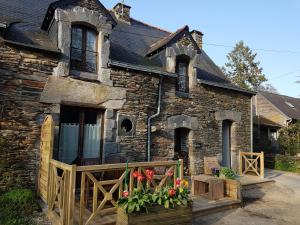 un antiguo edificio de piedra con porche y flores delante en Gîte Blé Noir Le Clos du Tay, en La Gacilly