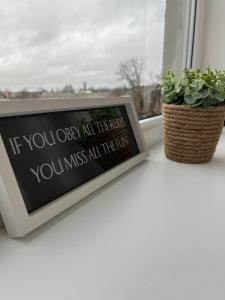 a framed picture on a window sill next to a plant at ESSE Apartament in Gulbene